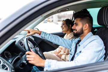 Enjoy life fun indian couple driving car at high speed and point fingers forward.