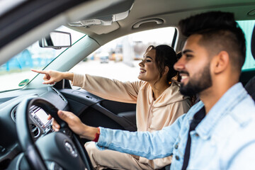 Enjoy life fun indian couple driving car at high speed and point fingers forward.