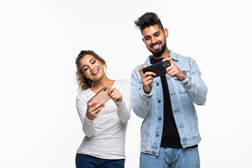 Young indian couple standing playing games on mobile phones, on a white background
