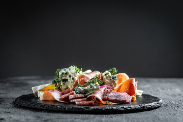 Antipasto with traditional Spanish meat snacks on a slate board, Antipasto platter. catering, banner, menu, recipe