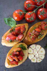 Tasty bruschetta with roasted tomatoes and basil. Close up photo of  toasted bread and fresh vegetables. Authentic Italian food. 