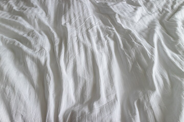 Wrinkled clean white bedsheet on a bed closeup texture. Stock photo