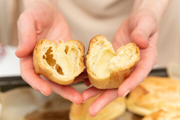 Chef shows the middle of workpiece for profiteroles, puffs, popovers, eclair. Close up