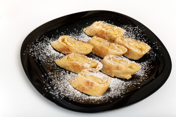 Apple roll, strudel on black plate on white background.