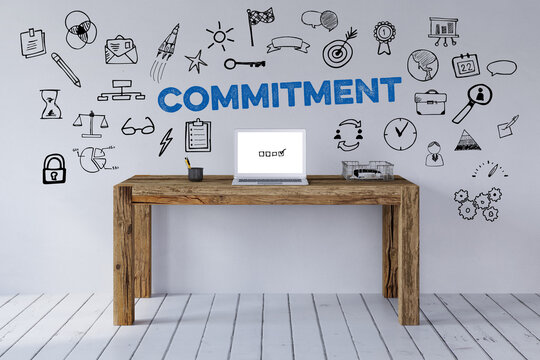 Schreibtisch mit Schriftzug Commitment und Icons