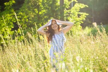 Young woman walking among wildflowers on sunny summer day. Concept of the joy of communicating with summer nature