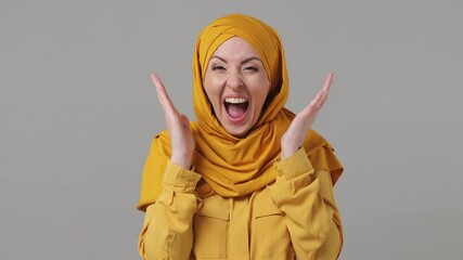 Joyful surprised shocked young arabian asian muslim woman in abaya hijab yellow clothes say wow what spreading hands isolated on grey gray background People uae middle eastern islam religious concept - Powered by Adobe
