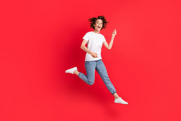 Fototapeta na wymiar Full length body size view of attractive funny cheerful girl jumping playing invisible guitar having fun isolated over bright red color background