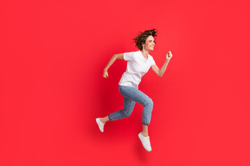 Fototapeta na wymiar Full length body size view of attractive motivated cheerful girl jumping running fast isolated over bright red color background