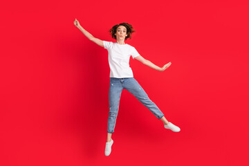 Full length body size view of nice funny skinny girl jumping having fun holding invisible parasol isolated over bright red color background