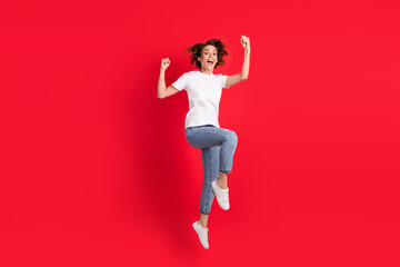 Full length body size view of attractive cheerful girl jumping rejoicing having fun isolated over bright red color background