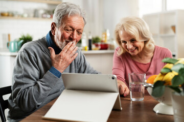 Senior couple having video call. Happy husband and wife talking with their grandkids.