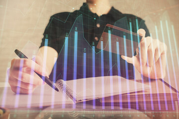 Double exposure of man hands holding a credit card and Forex graph drawing. Stock trading and digital fintech in Internet E-commerce concept.