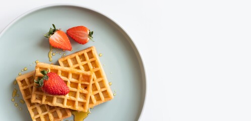waffles with honey and sliced strawberry isolated on plate. 