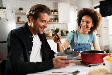 Boyfriend and girlfriend eating lunch with friends at home. Young couple enjoying the company of their friends