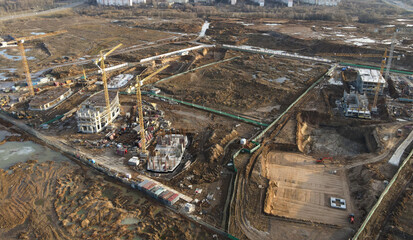 Drone view of a large construction site. Tower cranes in action on fog background. Housing...