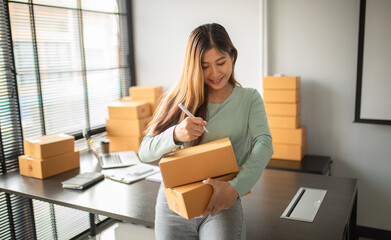 Portrait of Starting small businesses SME owners female entrepreneurs Write the address on receipt box and check online orders, prepare to pack the boxes, sell,customers, sme business ideas online.