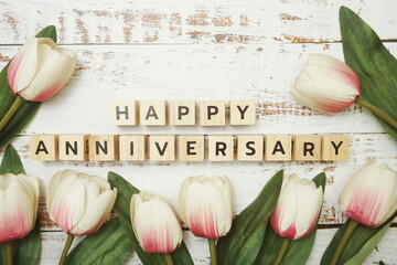 Happy Anniversary alphabet letter with tulip flower bouquet on wooden background