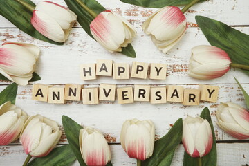Happy Anniversary alphabet letter with tulip flower bouquet on wooden background