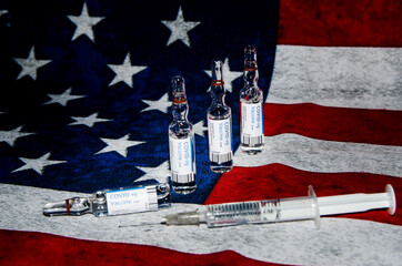Covid-19 vaccination. Bottle with vaccine and syringe with USA flag background. Immunization. Pandemic of Coronavirus. United States flag and vaccine vials.