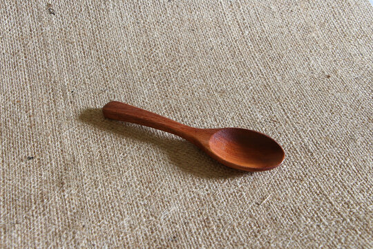 Wooden spoon on fabric hemp sack background.