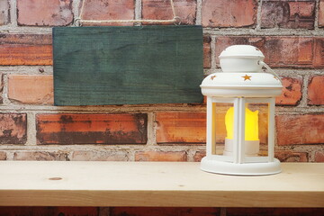 Empty wooden hanging on old brick wall with White lantern on wooden shelve