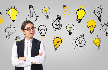 Young businesswoman with drawn light bulbs on grey background. Concept of business idea