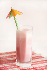 Tall glass with milkshake and parasol