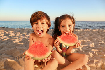 Cute little children eating watermelon on sea beach