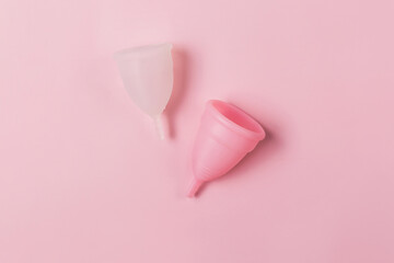 Two menstrual cups on the pink background. Decorated with a flower. Zero waste period concept.