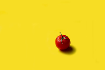 Red tomato on a yellow background, isolate