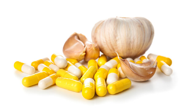 Fresh garlic with pills on white background