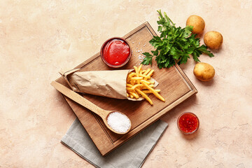 Tasty french fries with tomato sauce on color background