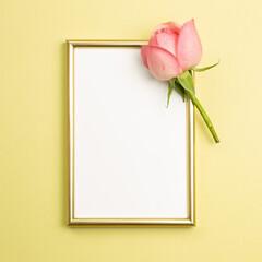 Picture frame with pink rose flower on yellow background. flat lay, top view, copy space