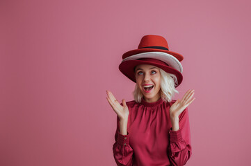 Funny girl with many hats on her head posing on pink background. Model looking up. Fashion, sale, shopping advertising conception. Copy, empty space for text