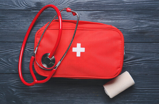 First aid kit, bandage and stethoscope on dark wooden background