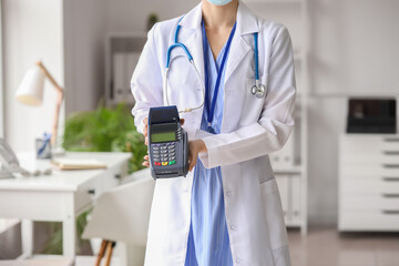 Doctor with payment terminal in clinic - obrazy, fototapety, plakaty