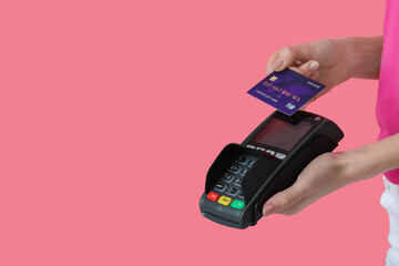 Young woman with payment terminal and credit card on color background, closeup