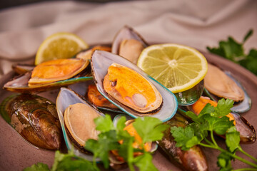 Naklejka na ściany i meble Fresh mussels in the sink lie on a large plate on a dark gray table, sea salt and parsley are scattered around the shells. The concept of healthy food and fresh seafood and delicacies.