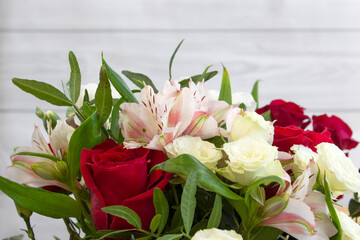 Bright burgundy and colored flowers in a bouquet on light wooden background close-up
