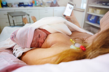 Obraz na płótnie Canvas Mother breast feeding newborn baby with phone