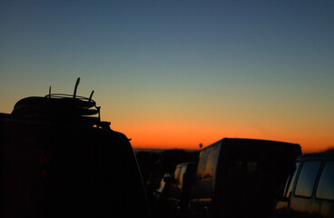 Obraz na płótnie Canvas Oranger Sonnenuntergang mit Surfbretter auf einem Autolack im vordergrund