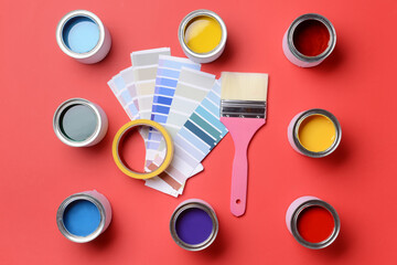 Cans of paints, palette samples, brush and tape on color background