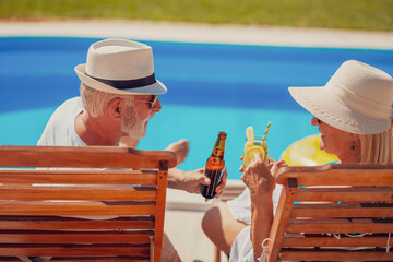 Senior couple making a toast by the swimming pool