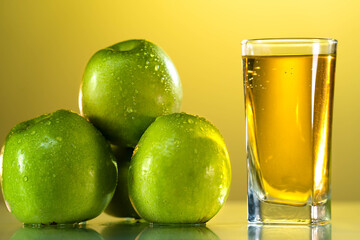One glass of apple juice with green apples in the sunset background. Reflected surface. Summer day. Good mood.