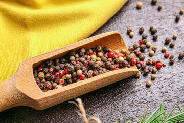 Scoop with mixed peppercorns on dark background, closeup