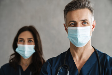 Two confident doctors in medical masks standing