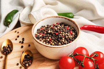 Bowl with mixed peppercorns and tomatoes on table