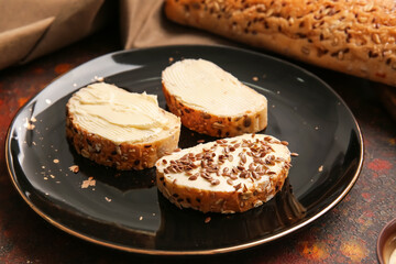 Plate with slices of fresh bread, butter and flax seeds on grunge background, closeup