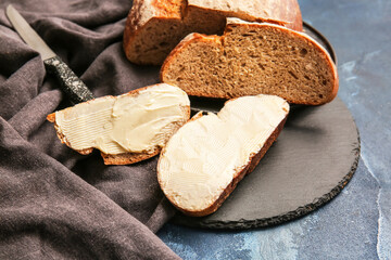 Fresh bread with butter on color background